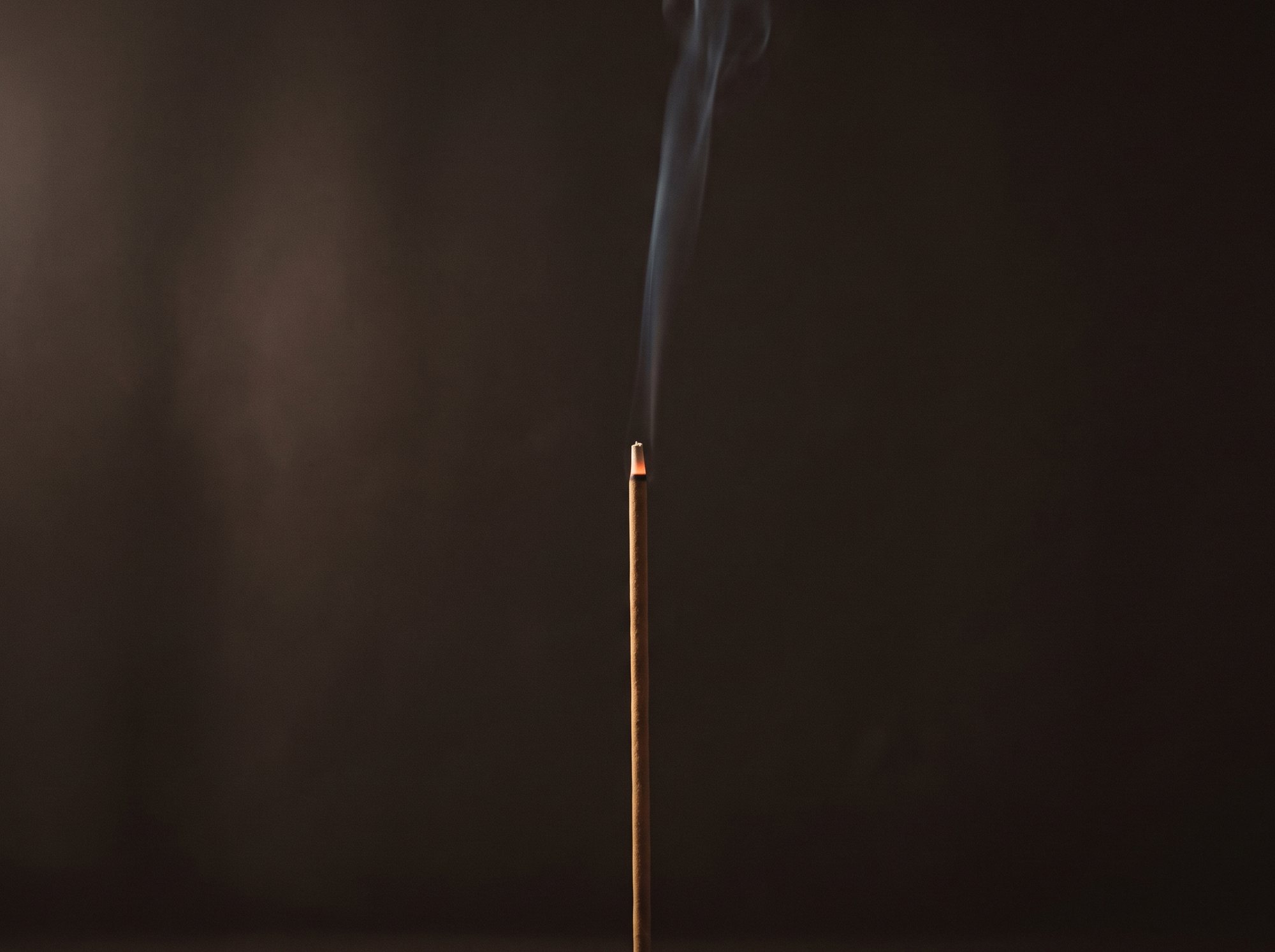 A fine trail of smoke rising from lit incense.