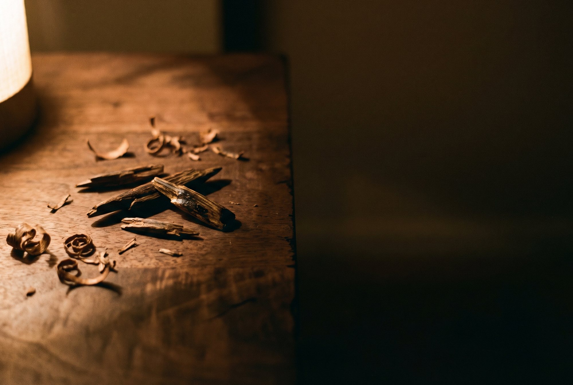 Resinous wood and fine shavings on a warmly lit wooden table.